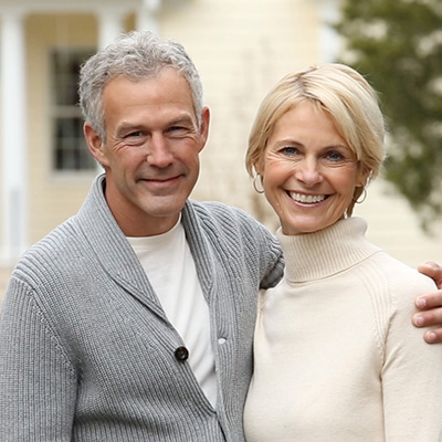 A senior couple standing infront of a home